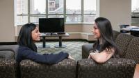 Two residents talking on a couch at the 11th floor lounge in the Bard hall